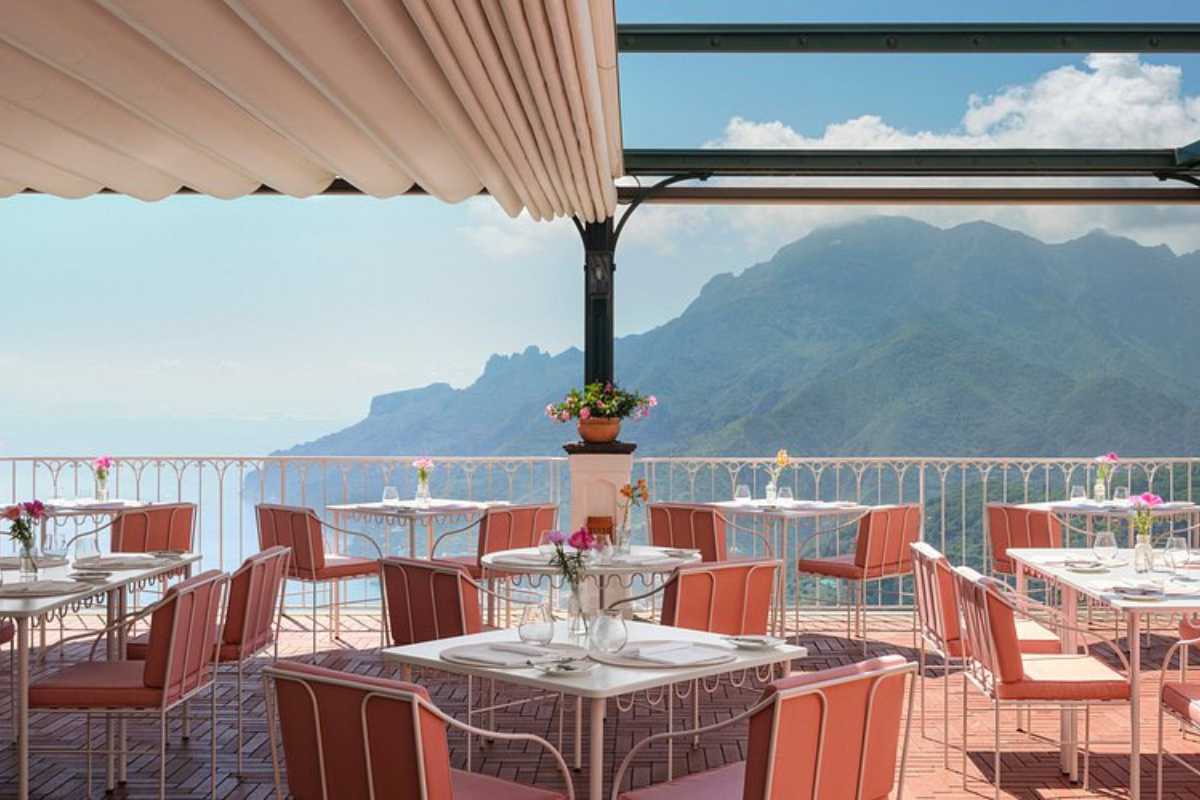 Fotografia di una tavola imbandita in una terrazza tipica di Ravello, con vista sul mare e sui limoneti, piatti tipici campani in primo piano